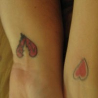 Tatuaje en la muñeca dos corazones en tinta roja
