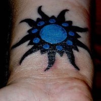 Sol en tinta negra y azul estilo tribal tatuaje en la muñeca