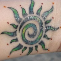 Sol en tinta verde estilo tribal tatuaje en la muñeca