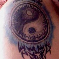 Yin yang tattoo with tribal elements on the shoulder