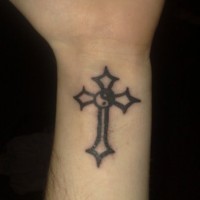 Le tatouage absurde de croix avec yin yang sur le poignet
