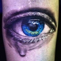 Tatuaje en la mano de una lagrima en un ojo azul.