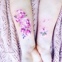 Tender pale pink peony flowers delicate watercolor like tattoo on girl's wrist