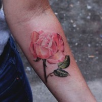 Tatuaje en el antebrazo, rosa delicada en tonos suaves