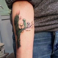 Tatuaje en el antebrazo,
árbol verde fantástico con tres monstruos divertidos diminutos