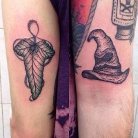 Tiny black ink detailed magic hat with leaf tattoo on arm