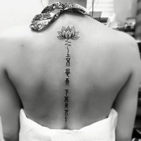 Tatuaje en la espalda, flor pequeña con sígnos misteriosos, tinta negra