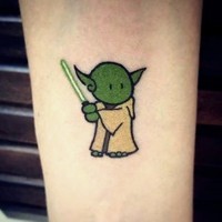 Tiny cartoon like little funny master Yoda with light saber tattoo on forearm area