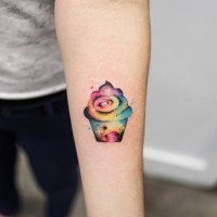 Tiny funny colored cupcake tattoo on forearm stylized with nigh sky