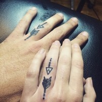 Tiny identical tribal arrows couple tattoo on fingers