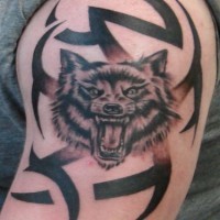 Tatuaggio sul deltoide la faccia del lupo con la bocca spalancata