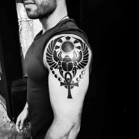 Tribal style black ink shoulder tattoo of big bug with cross