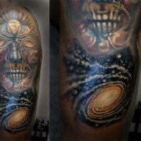 Tribal style monster mask tattoo on shoulder combined with space