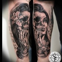 Typisches schwarzes Unterarm Tattoo von einem halb Schädel halb Frau Gesicht Tattoo mit Blumen