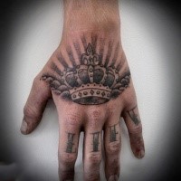 Typical black ink hand tattoo of crown with sun