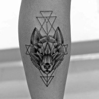 Typical black ink leg tattoo of wolf head with geometrical ornaments