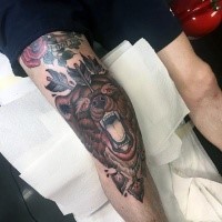 Typical multicolored knee tattoo of bear head with arrows