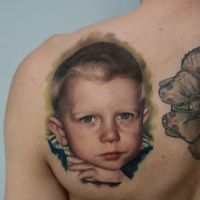 Typical portrait style colored and detailed scapular tattoo of little boy face