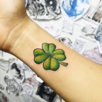 Typical small colored wrist tattoo of clover leaf
