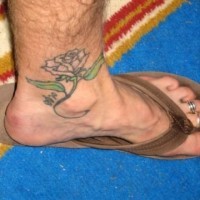 Uncolored rose with green leaves ankle tattoo