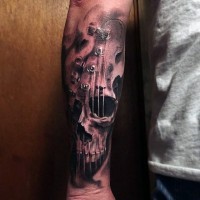Tatuaje en el antebrazo, cráneo humano con guitarra, idea interesante