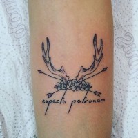 Unique combined tiny black ink spell lettering tattoo on forearm with mystic deer horns and flowers