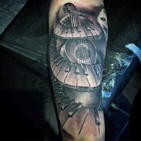Tatuaje en el brazo,
guitarra con teclas de piano, colores negro blanco