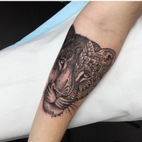 Unique designed black ink lion face tattoo on forearm stylized with flower ornaments