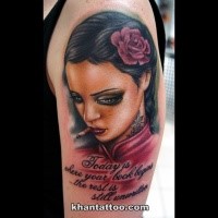 Illustrative style colored shoulder tattoo of woman portrait with flower and lettering