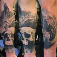 New school style colored forearm tattoo of human skull with bird and symbols