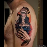 New school style colored shoulder tattoo of interesting looking bird with human hand