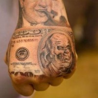Tatuaje en la mano,  billete de un dólar con cara de cráneo, idea interesante