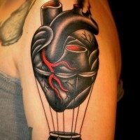 Tatuaje en el brazo, corazón humano negro con parte de globo