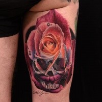 Unusual combined and colored thigh tattoo of rose with human skull