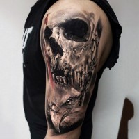 Unusual combined black and white detailed human skull tattoo on shoulder with eagle head