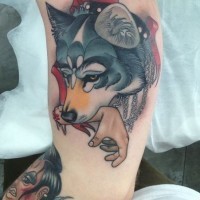 Tatuaje en el brazo, lobo amenazante con la mano humano en la boca