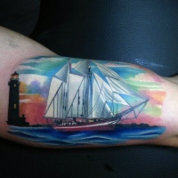 Usual colored biceps tattoo of modern sailing ship and lighthouse