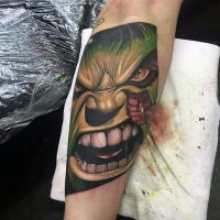 Usual designed colored angry Hulk face tattoo on forearm