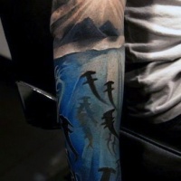 Usual half colored sleeve tattoo of sharks with and island