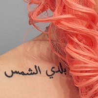 Tatuaje en el hombro, escrito árabe, tinta negra