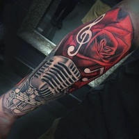 Tatuaje en el brazo, micrófono con rosa roja estupenda y notas