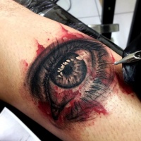 Very detailed leg tattoo of woman bloody eye