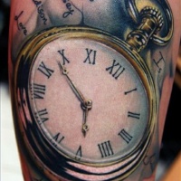 Very realistic looking antic golden pocket clock with lettering tattoo on arm