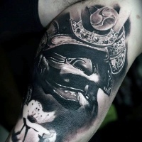 Tatuaje en el brazo,
casco volumétrico de samurái y flores de cerezo