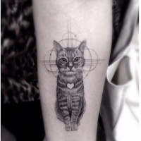 Very realistic looking black and white little cat with heart tattoo on arm