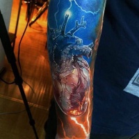 Very realistic looking colored heart with lightning tattoo on arm