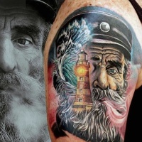 Very realistic looking colored old sailor with lighthouse tattoo on shoulder