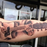 Very realistic looking musician playing the guitar tattoo on arm