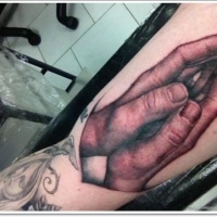 Very realistic painted and colored praying hands tattoo on arm