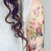 Tatuaje en el brazo, ramita de flores de varios colores suaves